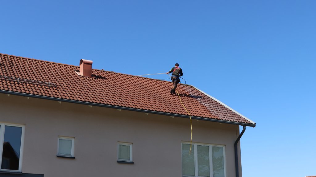 Professionell taktvätt i Enköping – en takspecialist rengör taket med säker utrustning.